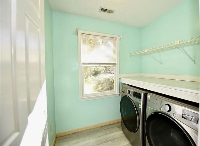 laundry area with laundry area, baseboards, visible vents, washer and dryer, and light wood-style floors