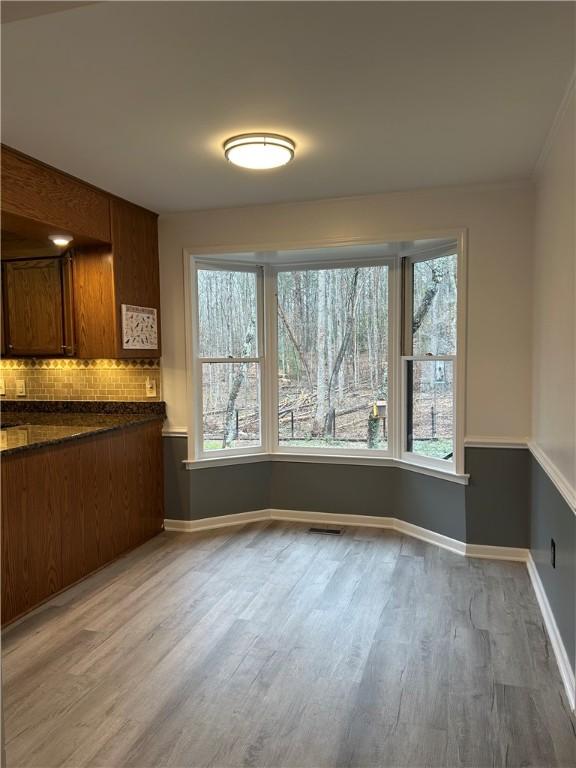 unfurnished dining area with light wood-type flooring, visible vents, and baseboards