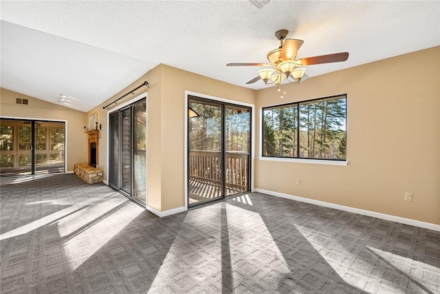 carpeted spare room with ceiling fan, vaulted ceiling, and a textured ceiling