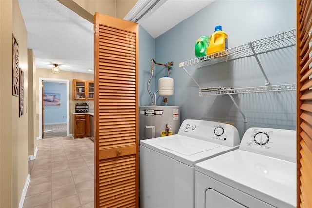 washroom featuring water heater, washer and dryer, light tile patterned floors, and a textured ceiling