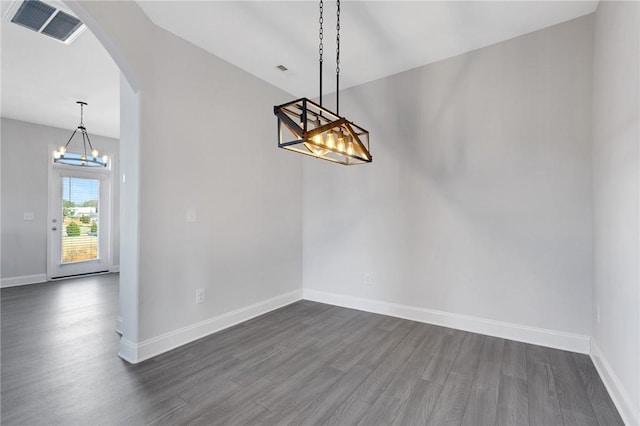 unfurnished dining area featuring dark hardwood / wood-style flooring and a chandelier