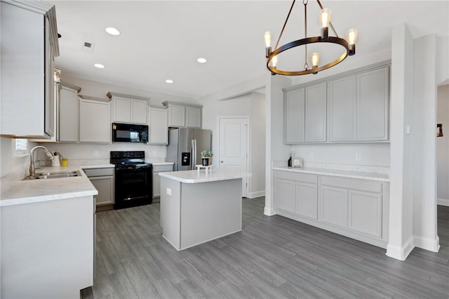 kitchen with sink, gray cabinetry, a center island, black appliances, and dark hardwood / wood-style flooring