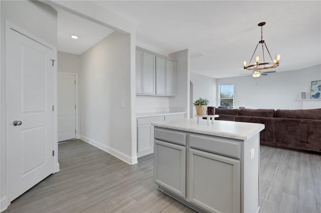 kitchen with pendant lighting, gray cabinets, a kitchen island, and light hardwood / wood-style flooring