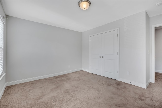 unfurnished bedroom featuring light carpet, multiple windows, and a closet