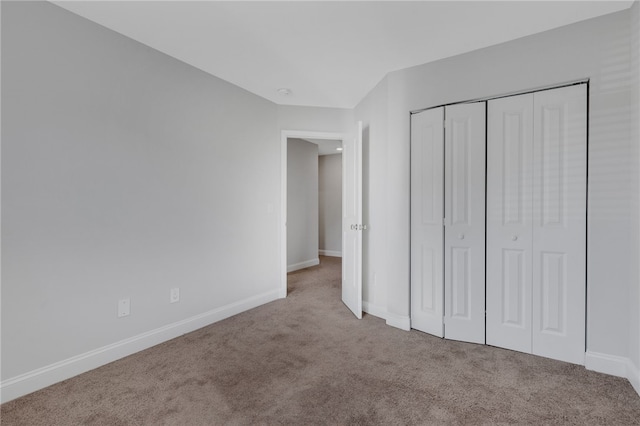 unfurnished bedroom with light colored carpet and a closet