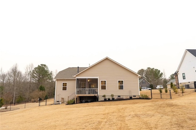 back of house featuring fence, a sunroom, crawl space, a lawn, and a gate