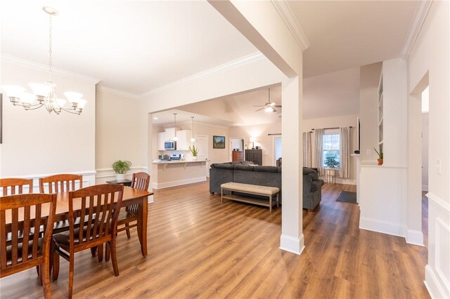 dining area with hardwood / wood-style flooring, crown molding, and ceiling fan with notable chandelier