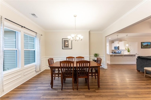 dining space featuring visible vents, ornamental molding, dark wood-type flooring, wainscoting, and a chandelier