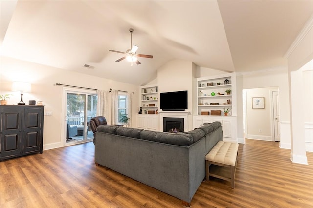 living area featuring lofted ceiling, a fireplace, wood finished floors, visible vents, and built in features