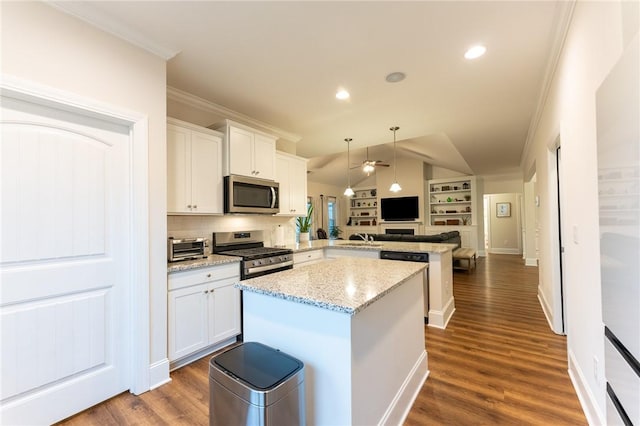 kitchen featuring crown molding, appliances with stainless steel finishes, open floor plan, a kitchen island, and a peninsula