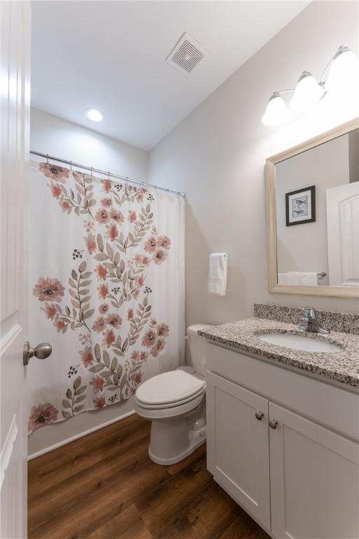 full bathroom featuring wood-type flooring, shower / tub combo with curtain, vanity, and toilet