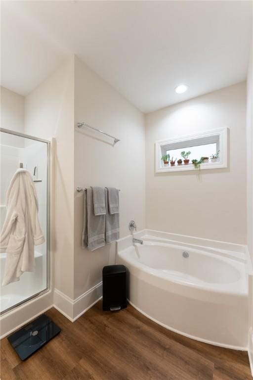 full bath with recessed lighting, a stall shower, wood finished floors, baseboards, and a bath