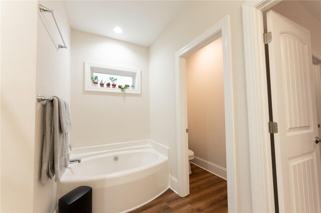 bathroom with toilet, a bathtub, and hardwood / wood-style floors