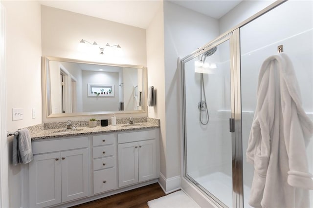 bathroom featuring an enclosed shower, vanity, and wood-type flooring