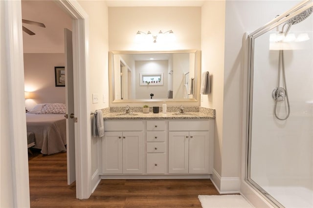 ensuite bathroom featuring a shower stall, connected bathroom, a sink, and wood finished floors