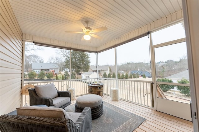 sunroom / solarium featuring a residential view and a ceiling fan