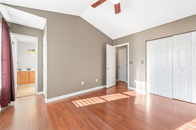 unfurnished bedroom with sink, vaulted ceiling, a closet, ceiling fan, and hardwood / wood-style floors