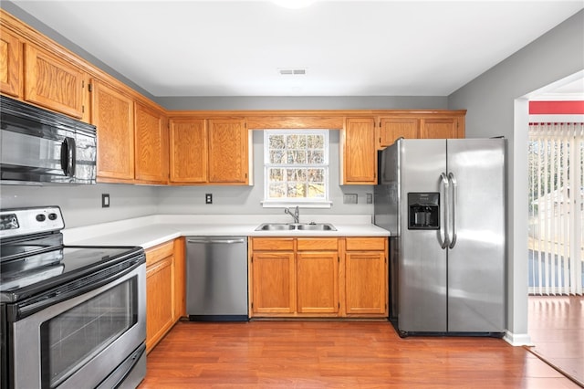 kitchen with sink, light wood-type flooring, and appliances with stainless steel finishes