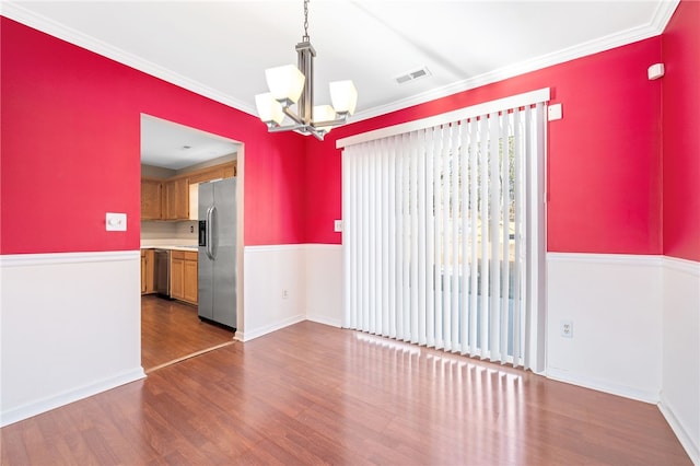 unfurnished room with an inviting chandelier, ornamental molding, and dark hardwood / wood-style floors