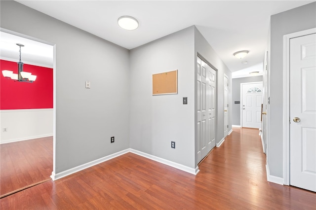 hallway featuring hardwood / wood-style flooring and an inviting chandelier