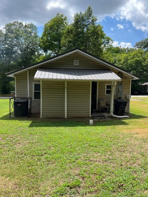 rear view of property with a yard and central AC unit