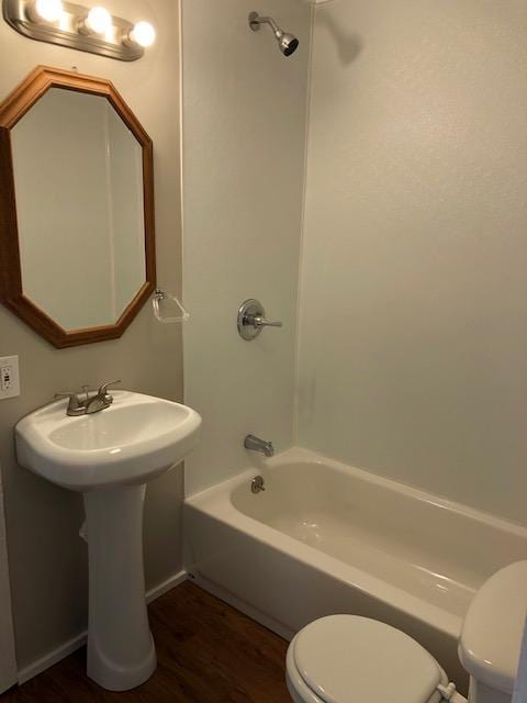 bathroom with wood-type flooring, toilet, and washtub / shower combination