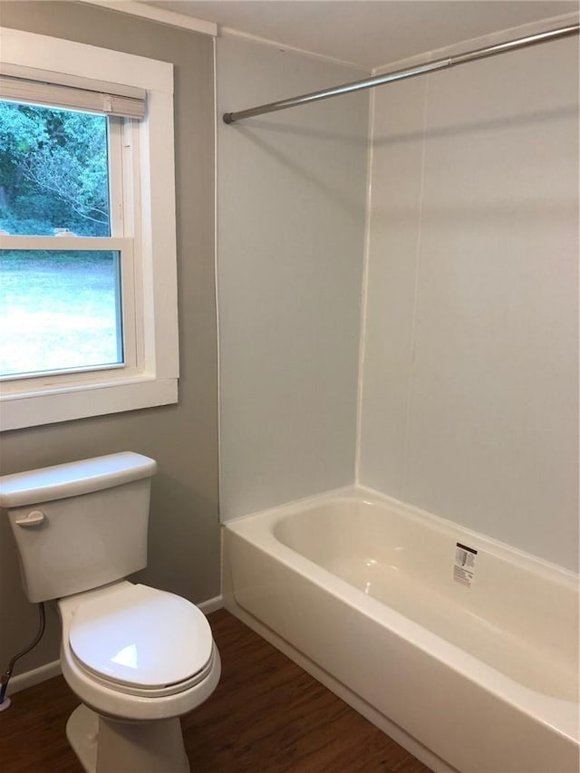 bathroom featuring wood-type flooring, toilet, and bathing tub / shower combination