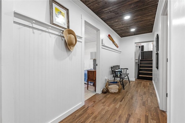 hall featuring crown molding, baseboards, wooden ceiling, wood finished floors, and stairway