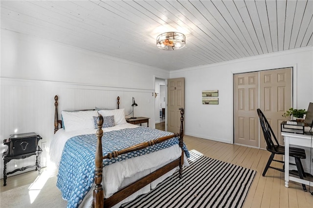 bedroom with wainscoting, ornamental molding, and light wood-style floors