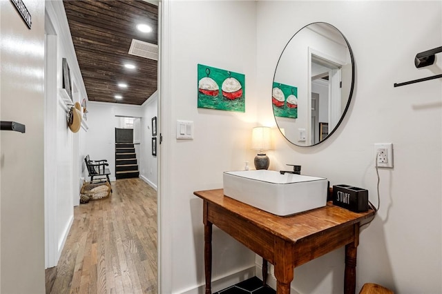 hallway with wood finished floors, a sink, baseboards, wooden ceiling, and recessed lighting