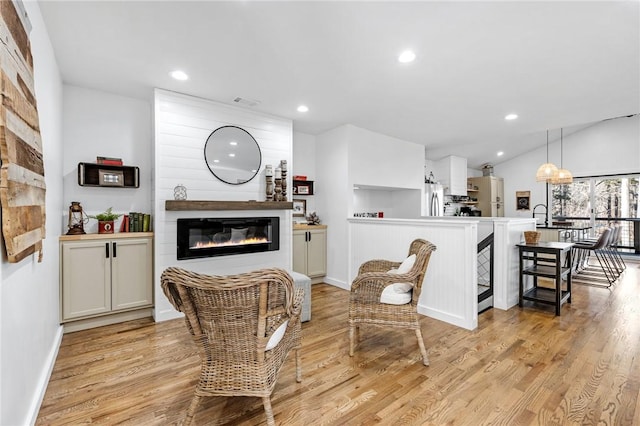 living room with lofted ceiling, a large fireplace, and light wood-type flooring