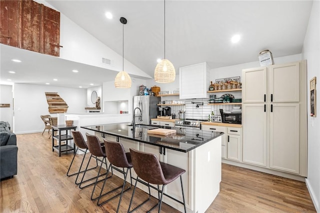 kitchen featuring visible vents, a breakfast bar, light wood-type flooring, a sink, and stainless steel appliances