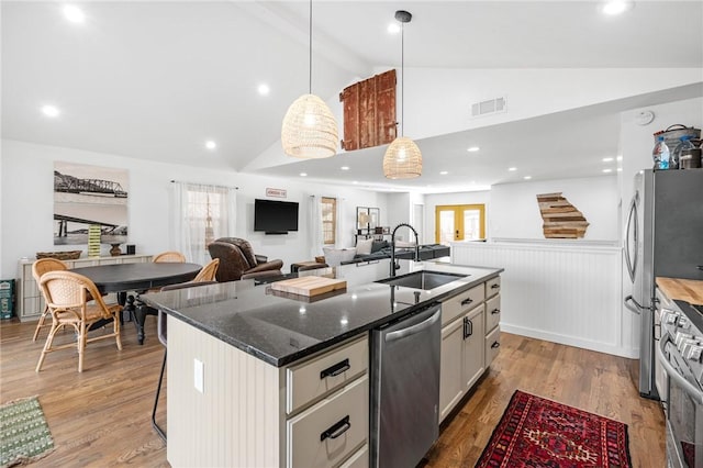 kitchen with visible vents, a center island with sink, a sink, beamed ceiling, and stainless steel appliances