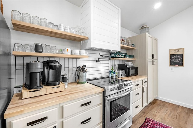 kitchen with stainless steel range with electric cooktop, open shelves, wooden counters, light wood-type flooring, and backsplash