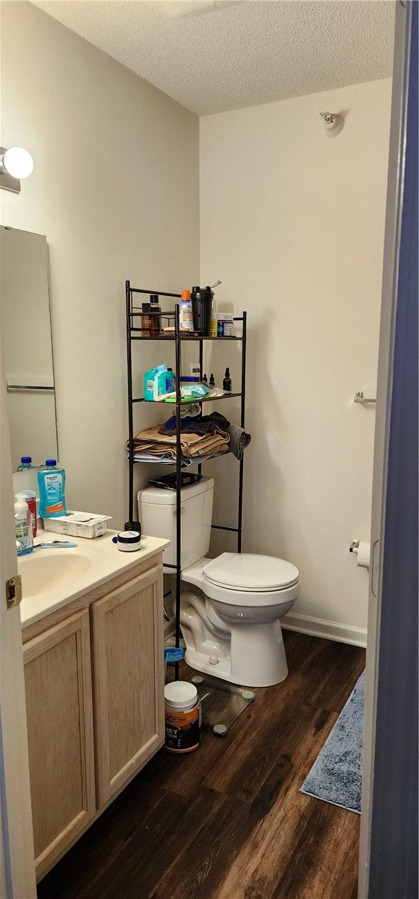 bathroom featuring vanity, toilet, hardwood / wood-style floors, and a textured ceiling