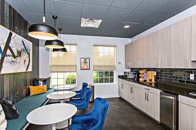 kitchen with pendant lighting, light brown cabinetry, tasteful backsplash, and a drop ceiling