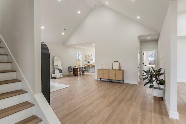 foyer entrance featuring a wealth of natural light, high vaulted ceiling, and light hardwood / wood-style floors