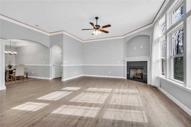 unfurnished living room with crown molding, ceiling fan with notable chandelier, a tile fireplace, and light wood-type flooring