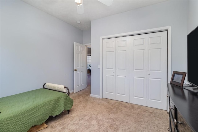 bedroom with light carpet, ceiling fan, and a closet