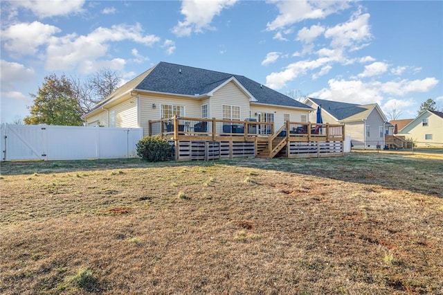 rear view of property featuring a deck and a lawn