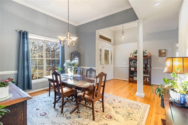 dining space featuring ornate columns, wood-type flooring, a wealth of natural light, and an inviting chandelier