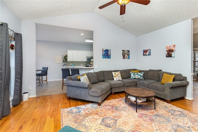 living room featuring ceiling fan, vaulted ceiling, and light wood-type flooring