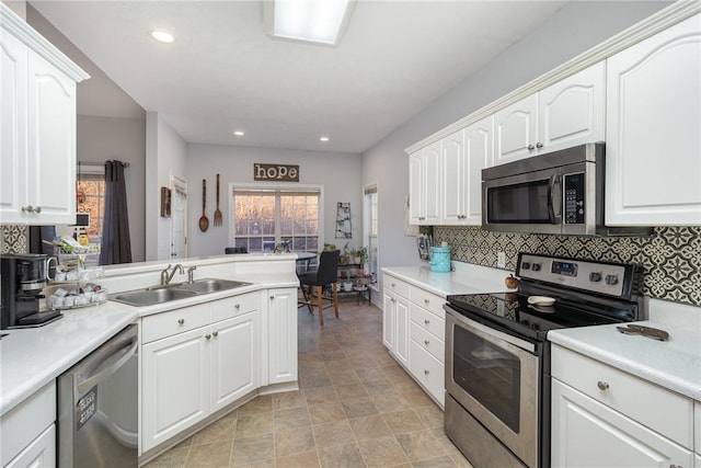 kitchen with sink, tasteful backsplash, kitchen peninsula, stainless steel appliances, and white cabinets