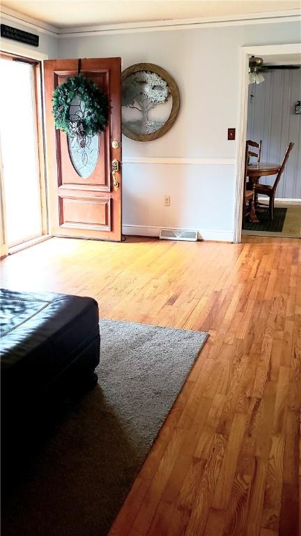 foyer featuring wood-type flooring and ornamental molding