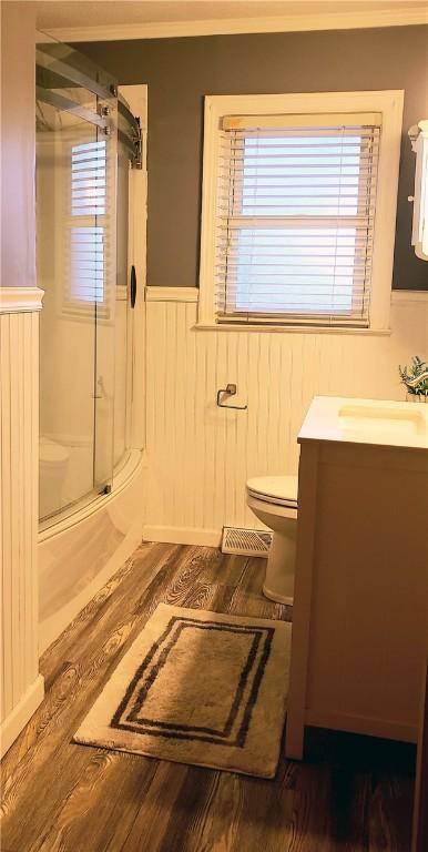 full bathroom with vanity, hardwood / wood-style floors, shower / bath combination with glass door, and toilet