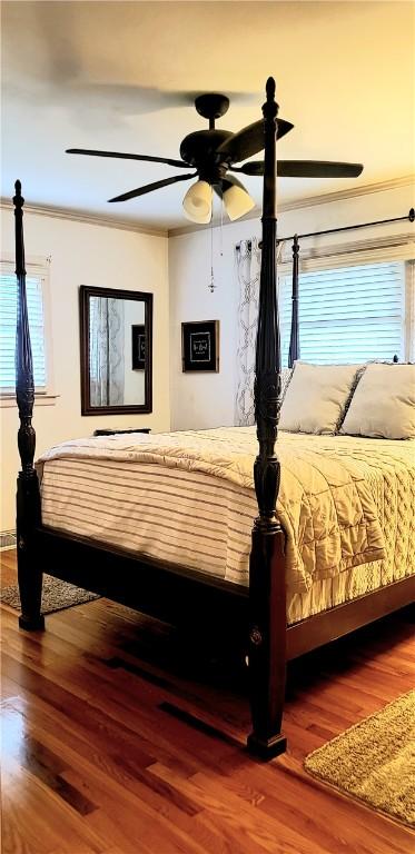 bedroom featuring hardwood / wood-style flooring, ceiling fan, and crown molding