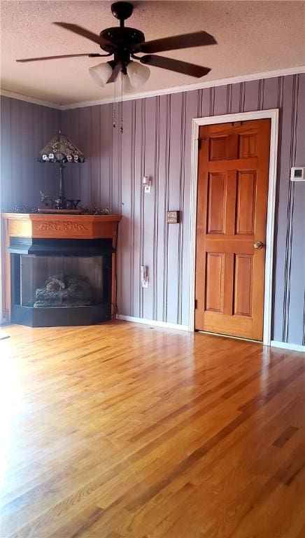 unfurnished living room featuring ceiling fan, ornamental molding, hardwood / wood-style floors, and a textured ceiling