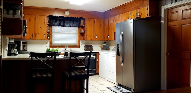 kitchen with washer / clothes dryer, light tile patterned floors, sink, and stainless steel refrigerator with ice dispenser