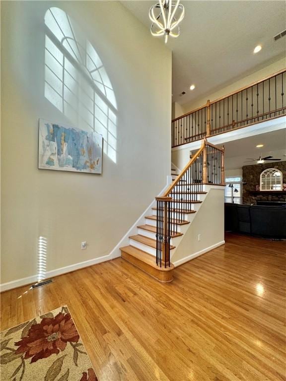 stairway featuring hardwood / wood-style floors, a notable chandelier, and a towering ceiling