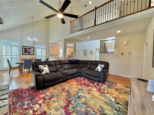 living room featuring wood-type flooring, ceiling fan with notable chandelier, and high vaulted ceiling